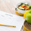 diet plan paper with green apple, measuring tape and salad