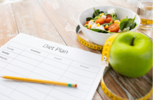 diet plan paper with green apple, measuring tape and salad