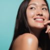 Close up of cute asian girl with glowing skin against blue background. Beautiful face of girl with fresh healthy skin.