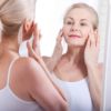 Middle aged woman looking at wrinkles in mirror