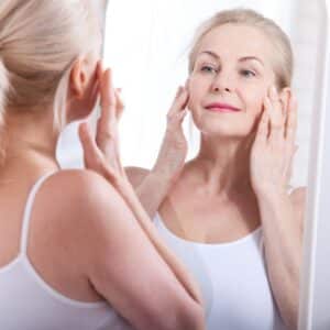 Middle aged woman looking at wrinkles in mirror