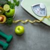 Green apple and Weight scale measure tap with nutrition vegan vegetable and sport equipment gym for body women diet fit.
