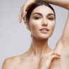 What Causes Skin Tags (And Why You Might Be Prone to Them) Woman raises her arms to reveal smooth underarm without skin tag