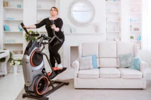 Woman on home elliptical is trying to lose weight with exercise.