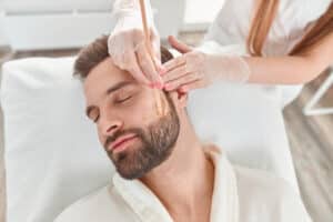 Man in robe gets a facial from a cosmetic dermatologist for improved skin texture.