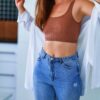 Woman in jeans showing her slim midsection from weight loss program