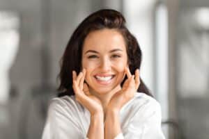 Smiling woman checking her complexion before a personalized VISIA skin analysis.